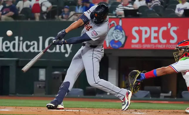 Detroit Tigers' Riley Greene, left, hits a home run in front of Texas Rangers catcher Kyle Higashioka, right, during the first inning of a baseball game, Saturday, July 4, 2026, in Arlington, Texas. (AP Photo/LM Otero)