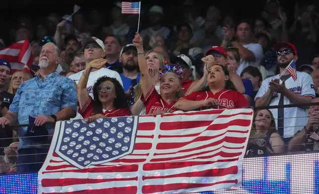 Fans stand for the national anthem before a baseball game between the Detroit Tigers and Texas Rangers, Saturday, July 4, 2026, in Arlington, Texas. (AP Photo/LM Otero)