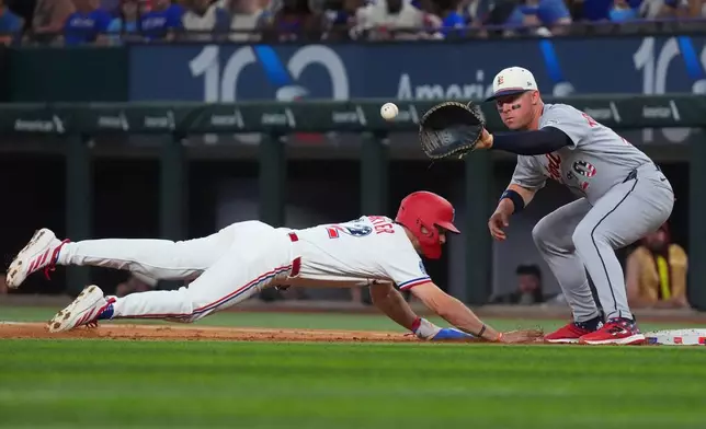 Texas Rangers' Evan Carter, left, dives to first base, beating a pickoff throw to Detroit Tigers first baseman Spencer Torkelson, right, during the second inning of a baseball game, Saturday, July 4, 2026, in Arlington, Texas. (AP Photo/LM Otero)