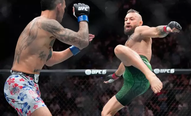 Conor McGregor, right, jumps into the air for a kick as he fights Max Holloway in a welterweight fight at the UFC 329 mixed martial arts event Saturday, July 11, 2026, in Las Vegas. (AP Photo/John Locher)