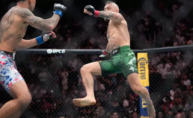 Conor McGregor, right, jumps into the air for a kick as he fights Max Holloway in a welterweight fight at the UFC 329 mixed martial arts event Saturday, July 11, 2026, in Las Vegas. (AP Photo/John Locher)