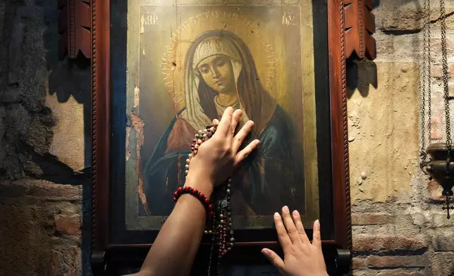 Catholics touch one of the images of Mary inside the Ephesus House, a replica of the House of the Virgin Mary in Ephesus, Turkey, at Alfonso town, Cavite province, Philippines on July 16, 2026. (AP Photo/Aaron Favila)