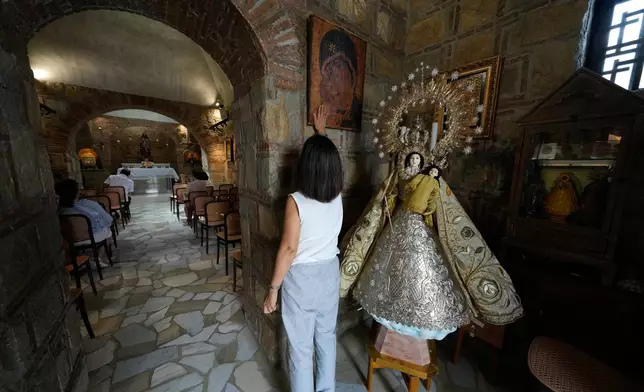 A Catholic devotee touches a religious icon during her visit at the Ephesus House, a replica of the House of the Virgin Mary in Ephesus, Turkey, at Alfonso town, Cavite province, Philippines on July 16, 2026. (AP Photo/Aaron Favila)