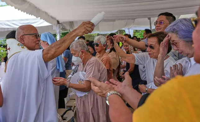 Catholic priest Father Dennis Paez sprinkles holy water to pilgrims during their visit at the Ephesus House, a replica of the House of the Virgin Mary in Ephesus, Turkey, at Alfonso town, Cavite province, Philippines on July 16, 2026. (AP Photo/Aaron Favila)
