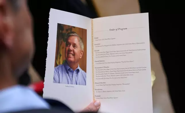 A guest looks at the program during the service for Sen. Lindsey Graham of South Carolina, in the Rotunda of the U.S. Capitol, Tuesday, July 28, 2026, in Washington. (AP Photo/Allison Robbert)
