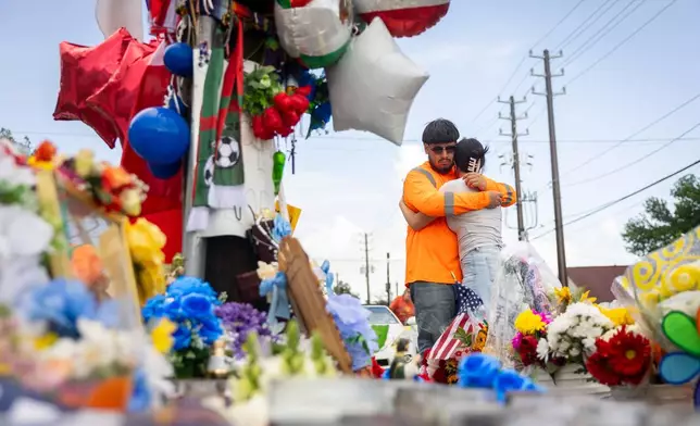 Albert Salgado is comforted by his girlfriend at the site where his uncle Lorenzo Salgado Araujo was shot by an ICE officer in Houston on Friday, July 10, 2026. (AP Photo/Annie Mulligan)