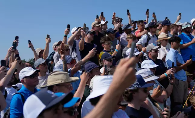 Spectators hold up their phones to capture Rory McIlroy of Northern Ireland and Shane Lowry of Ireland during their practice round for the British Open Golf championships at Royal Birkdale golf club, in Southport, England, Wednesday, July 15, 2026. (AP Photo/David Goldman)