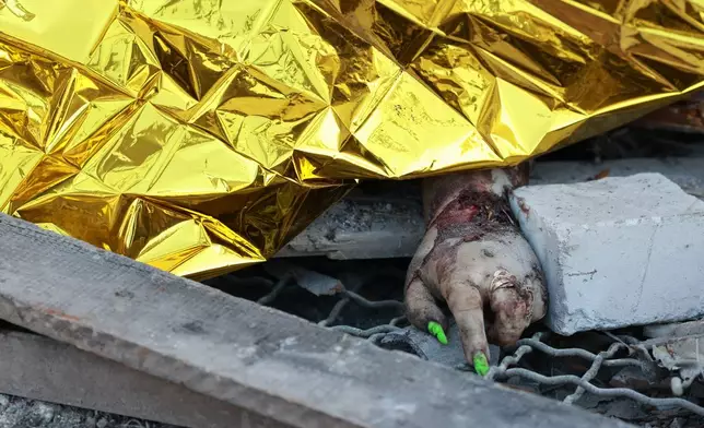 The body of a local resident is covered after a Russian air guided bomb hit private houses in Zaporizhzhia, Ukraine, Thursday, July 16, 2026. (AP Photo/Kateryna Klochko)