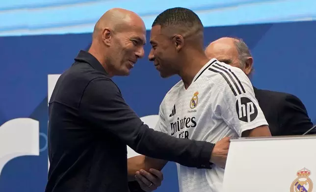 FILE - Former French player Zinedine Zidane, left, embraces Kylian Mbappe of France, as he is being presented to fans as a new Real Madrid player in Madrid, July 16, 2024. (AP Photo/Andrea Comas, File)