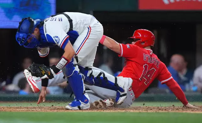 Los Angeles Angels' Logan O'Hoppe (14) is out at home plate against Texas Rangers catcher Kyle Higashioka (11) on a bases loaded force out during the seventh inning of a baseball game, Thursday, July 9, 2026, in Arlington, Texas. (AP Photo/LM Otero)
