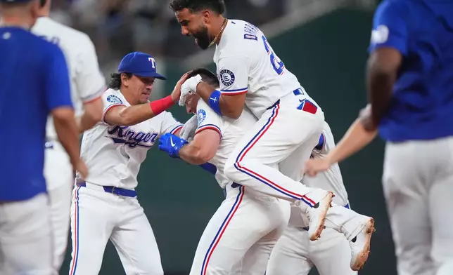 Texas Rangers' Ezequiel Duran (20) and Nicky Lopez, left, celebrates with Wyatt Langford a game winning single in the ninth inning of a baseball game against the Los Angeles Angels, Thursday, July 9, 2026, in Arlington, Texas. (AP Photo/LM Otero)