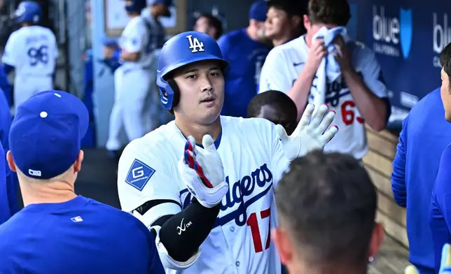 Los Angeles Dodgers' Shohei Ohtani is greeted by teammates after hitting a home run during the first inning of a baseball game against the Arizona Diamondbacks, Friday, July 10, 2026, in Los Angeles. (AP Photo/William Liang)