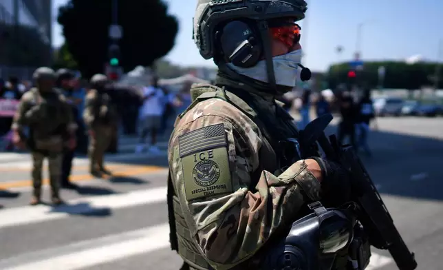 FILE - An ICE Special Response Team member stands guard outside the Metropolitan Detention Center, while protesters gather outside to denounce the ICE, U.S. Immigration and Customs Enforcement, operations, June 10, 2025, in downtown Los Angeles. (AP Photo/Eric Thayer, File)