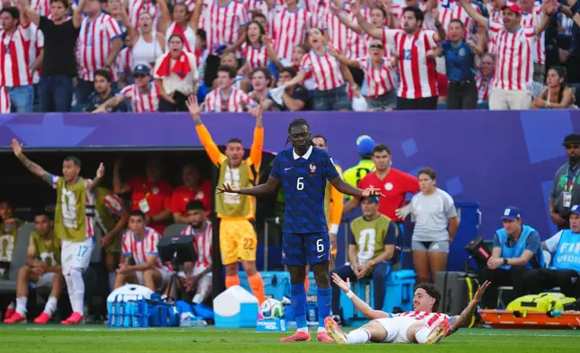 France's Manu Kone, center, and Paraguay's Mauricio, on the ground, gesture during the World Cup round of 16 soccer match between Paraguay and France in Philadelphia, Saturday, July 4, 2026. (AP Photo/Derik Hamilton)