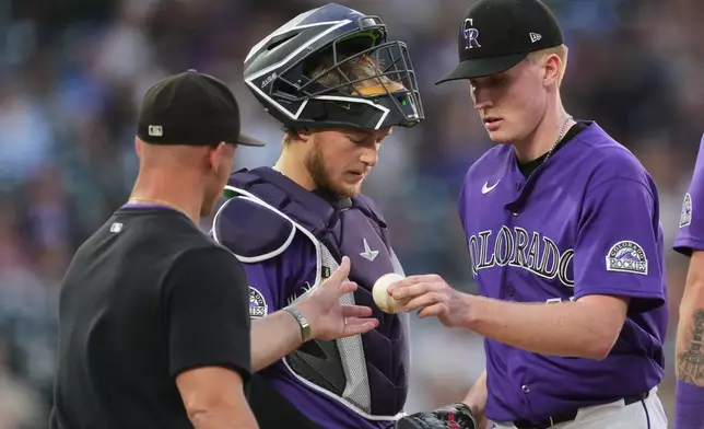 Colorado Rockies starting pitcher Sean Sullivan, right, hands the ball to manager Warren Schaeffer, left, as catcher Hunter Goodman, center, stands by as he is pulled form the mound after issuing a walk to Miami Marlins' Kyle Stowers in the fifth inning of a baseball game Monday, June 29, 2026, in Denver. (AP Photo/David Zalubowski)