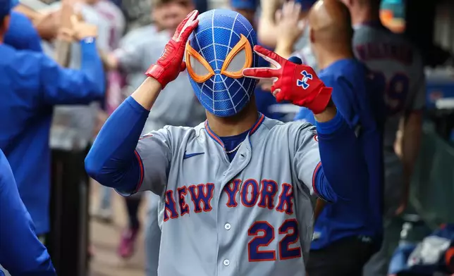 New York Mets' Juan Soto (22) reacts in the dugout with a Spiderman mask after hitting a tying two-run home run in the third inning of a baseball game against the Atlanta Braves, Friday, July 3, 2026, in Atlanta. (AP Photo/Colin Hubbard)