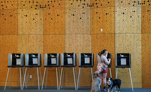 Danielle Grisolano brings her dogs Lincoln and Pepper with her to vote in the Democratic primaries at Denver Public Library, Tuesday, June 30, 2026, in Denver. (AP Photo/Rebecca Slezak)
