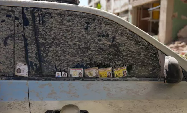 Identification cards and photographs of missing people are left on the window of a dirt-covered car by relatives searching for information in Catia La Mar, Venezuela, Saturday, June 27, 2026, three days after twin earthquakes struck the country. (AP Photo/Fernando Vergara)