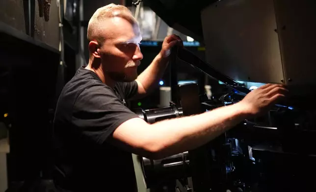 Tomas Vysinsky prepares the 70 mm IMAX copy of Christopher Nolan's "The Odyssey" for screening in Prague, Czech Republic, Monday, July 27, 2026. (AP Photo/Petr David Josek)