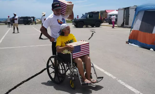 People affected by the earthquakes carry U.S. humanitarian aid after receiving it in La Guaira, Venezuela, Wednesday, July 8, 2026. (AP Photo/Ariana Cubillos)
