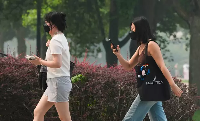 People wear masks as they walk on the street during poor air quality due to dense smoke from Canadian wildfires in Evanston, Ill., Thursday, July 16, 2026. (AP Photo/Nam Y. Huh)