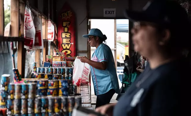Volunteers Laurene Cardoza, foreground, and Jennifer Aragon work at a TNT Fireworks stand in Alhambra, Calif., Tuesday, June 30, 2026, ahead of the Fourth of July holiday. (AP Photo/Jae C. Hong)