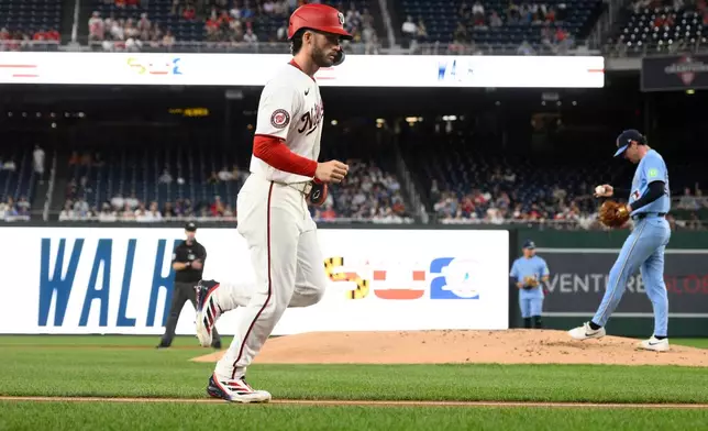 Washington Nationals' Dylan Crews, left, goes towards home to score on a bases loaded walk to Daylen Lile against Toronto Blue Jays pitcher Shane Bieber, right, during the first inning of a baseball game, Tuesday, July 28, 2026, in Washington. (AP Photo/Nick Wass)