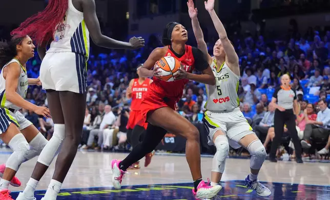 Atlanta Dream forward Angel Reese, center, drives against Dallas Wings guard Paige Bueckers (5) during the second half of a WNBA basketball game in Arlington, Texas, Wednesday, July 29, 2026. (AP Photo/LM Otero)