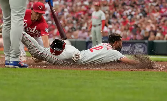 Philadelphia Phillies Justin Crawford dives in to home plate to score on a wild pitch as Cincinnati Reds pitcher Chase Burns, left, reaches in with a late tag during the second inning of a baseball game in Cincinnati, Wednesday, July 8, 2026. (AP Photo/Carolyn Kaster)