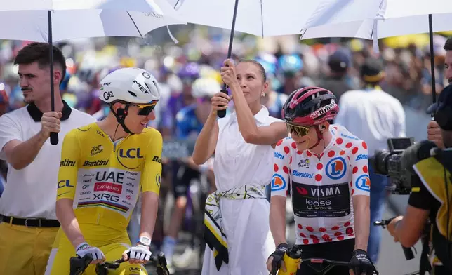 Slovenia's Tadej Pogacar, wearing the overall leader's yellow jersey, and Denmark's Jonas Vingegaard, wearing the best climber's dotted jersey, are shielded from the sun ahead of the start of the ninth stage of the Tour de France cycling race with start in Malemort and finish in Ussel, France, Sunday, July 12, 2026. (AP Photo/Mosa'ab Elshamy)