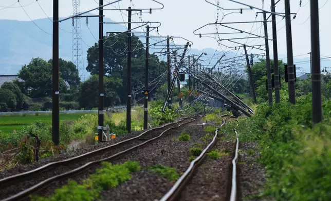 Electric poles are seen fallen over rail tracks in Hikawa, southern Japan, Thursday, July 30, 2026, two days after an earthquake hit the area. (AP Photo/Hiro Komae)