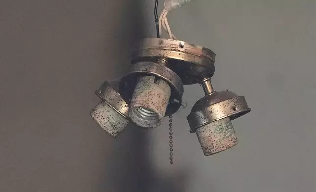 A hanging light fixture is seen through a broken window in a home where authorities say they removed 16 children and arrested four adults in Hamden, Ohio, Wednesday, July 1, 2026. (AP Photo/Carolyn Kaster)