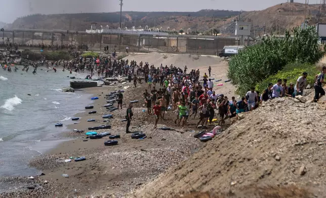 Migrants cross from Morocco into the Spanish enclave of Ceuta, Thursday, July 30, 2026. (AP Photo/Antonio Sempere)