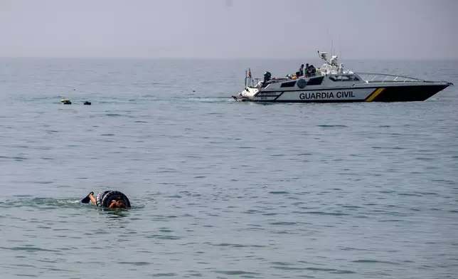 A migrant uses a rubber ring while trying to cross into the Spanish enclave of Ceuta from Morocco, Thursday, July 30, 2026. (AP Photo/Antonio Sempere)
