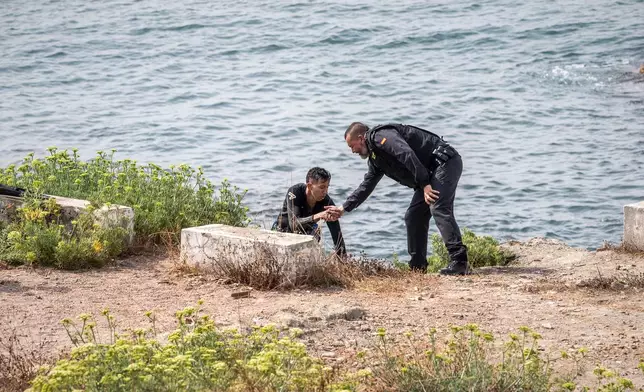 A migrant is assisted by a Spanish Civil Guard officer after swimming from Morocco to the Spanish enclave of Ceuta, Wednesday, July 29, 2026. (AP Photo/Antonio Sempere)