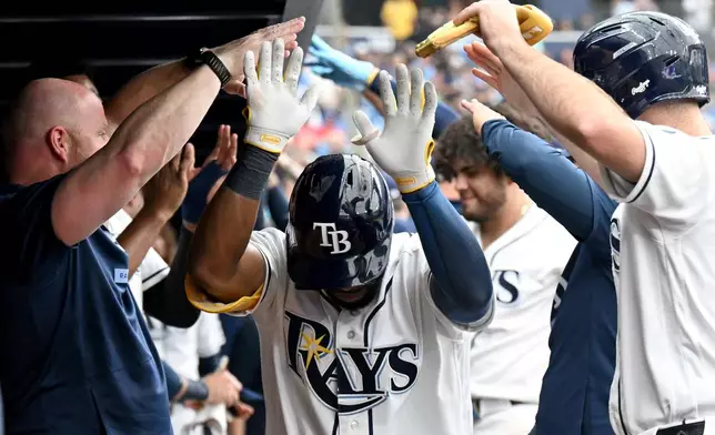 Tampa Bay Rays' Cedric Mullins is greeted in the dugout after hitting a home run during the eighth inning of a baseball game against the Texas Rangers, Thursday, July 30, 2026, in St. Petersburg, Fla. (AP Photo/Jason Behnken)