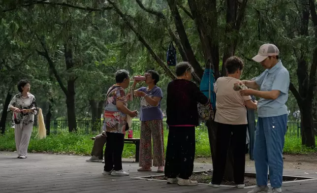 Women drink after practicing Tai Chi at a park near the Temple of Heaven in Beijing, Thursday July 9, 2026. (AP Photo/Andy Wong)