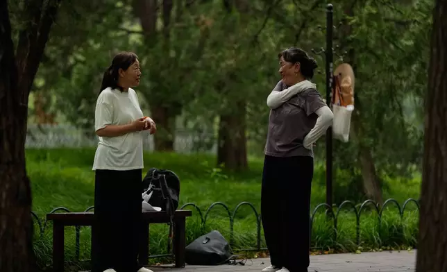 Ye Guirong, left, chats with Zu Hong after practicing Tai Chi at a park near the Temple of Heaven in Beijing, Thursday July 9, 2026. (AP Photo/Andy Wong)