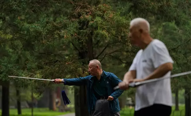 Elderly men practice Tai Chi with swords at a park near the Temple of Heaven in Beijing, Thursday July 9, 2026. (AP Photo/Andy Wong)