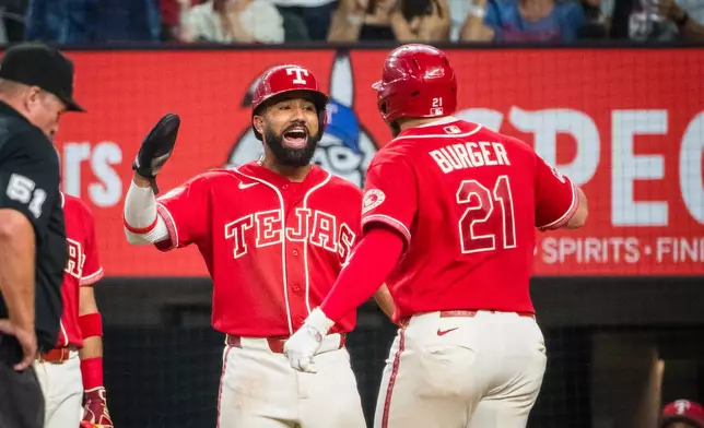 Texas Rangers' Jake Burger (21) is celebrates hitting a home run with Texas Rangers' Ezequiel Duran during the fourth inning of a baseball game against the Seattle Mariners, Friday, July 24, 2026, Arlington, Texas. (AP Photo/Jessica Tobias)