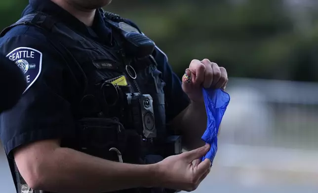 A police officer puts a bullet casing into a rubber glove after he received it from a person who found it, following a shooting at Seattle Center during the Bite of Seattle food festival, Monday, July 27, 2026, in Seattle. (AP Photo/Lindsey Wasson)