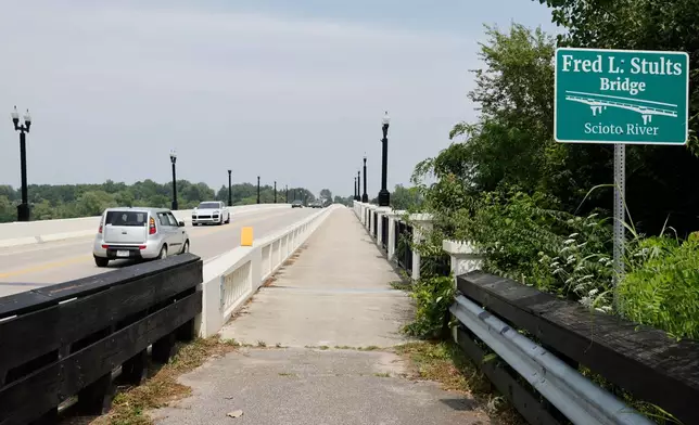 Cars drive on the Fred L, Stults Bridge over the Scioto River near where multiple people died after several of them went into the water to help another person who was struggling to swim Monday, July 20, 2026, in Powell, Ohio. (AP Photo/Jay LaPrete)