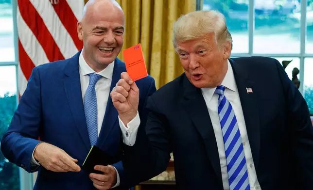 FILE - President Donald Trump holds up a red card during a meeting with FIFA president Gianni Infantino in the Oval Office of the White House, Tuesday, Aug. 28, 2018, in Washington. (AP Photo/Evan Vucci, File)
