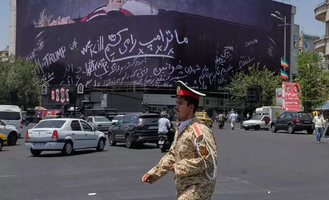 An army cadet walks past a billboard bearing anti-Trump messages, including the phrase "We Kill Trump," at Islamic Revolution Square in downtown Tehran, Iran, Wednesday, July 15, 2026. (AP Photo/Vahid Salemi)