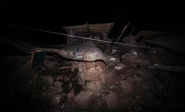 Lit candles stand amid the rubble of a house that collapsed after an earthquake struck Pumpuya, Peru, Sunday, July 19, 2026.( AP Photo/Javier Ninanya)