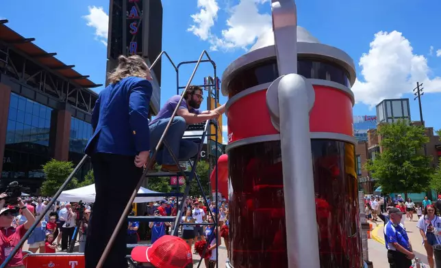 Eric Johnson and Guinness World Records adjudicator Thomas Bradford check the level of beer before certifying a world record for Largest Glass of Beer ahead of a baseball game between the Detroit Tigers and Texas Rangers, Saturday, July 4, 2026, in Arlington, Texas. (AP Photo/LM Otero)