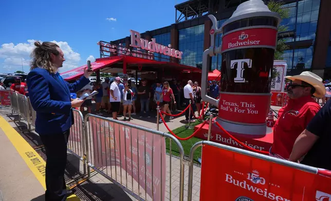 Guinness World Records adjudicator Thomas Bradford, left, makes a photo before certifying a world record for Largest Glass of Beer ahead of a baseball game between the Detroit Tigers and Texas Rangers, Saturday, July 4, 2026, in Arlington, Texas. (AP Photo/LM Otero)