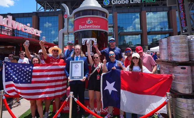 Guinness World Records adjudicator Thomas Bradford, center, cheers with others aftercertifying a world record for Largest Glass of Beer ahead of a baseball game between the Detroit Tigers and Texas Rangers, Saturday, July 4, 2026, in Arlington, Texas. (AP Photo/LM Otero)