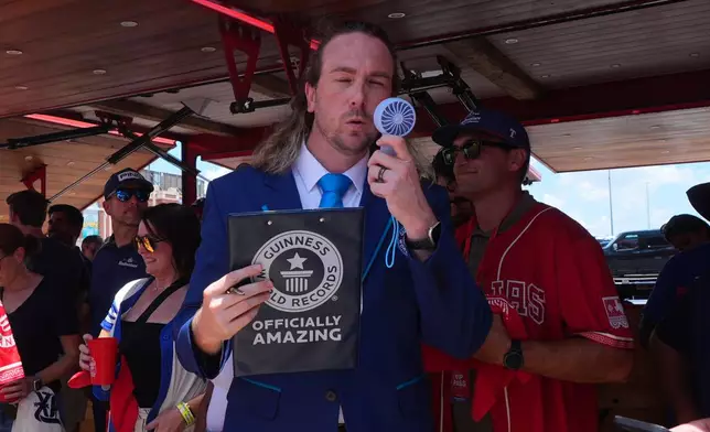 Guinness World Records adjudicator Thomas Bradford uses a fan to cool off before certifying a world record for Largest Glass of Beer ahead of a baseball game between the Detroit Tigers and Texas Rangers, Saturday, July 4, 2026, in Arlington, Texas. (AP Photo/LM Otero)