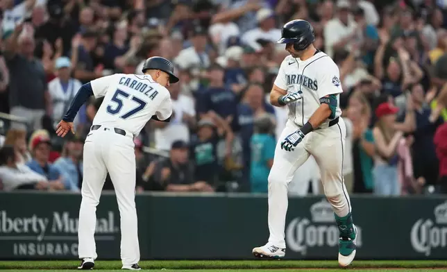Seattle Mariners' Cal Raleigh, right, greets third base coach Carlos Cardoza (57) as he jogs the bases after hitting a grand slam against the Cincinnati Reds during the seventh inning of a baseball game, Monday, July 20, 2026, in Seattle. (AP Photo/Lindsey Wasson)